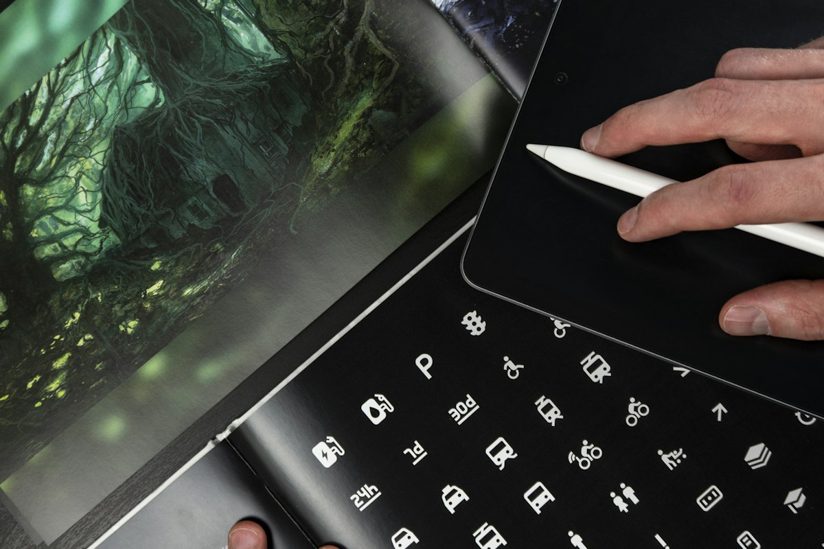 Designer working on a tablet over a portfolio of icons and visual identity work